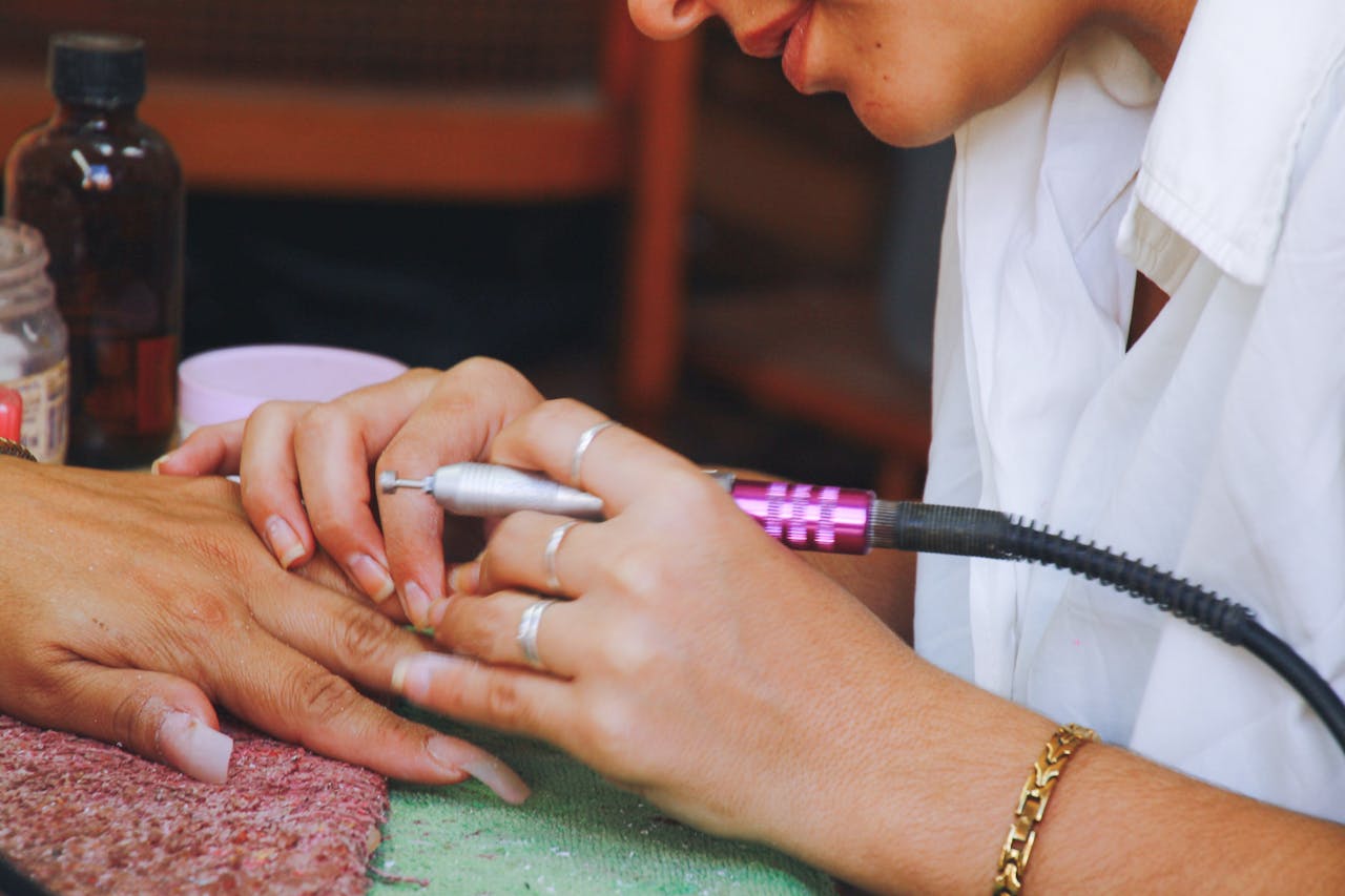 Close-up image of a nail technician using an electric file on a clients nails during a manicure session.