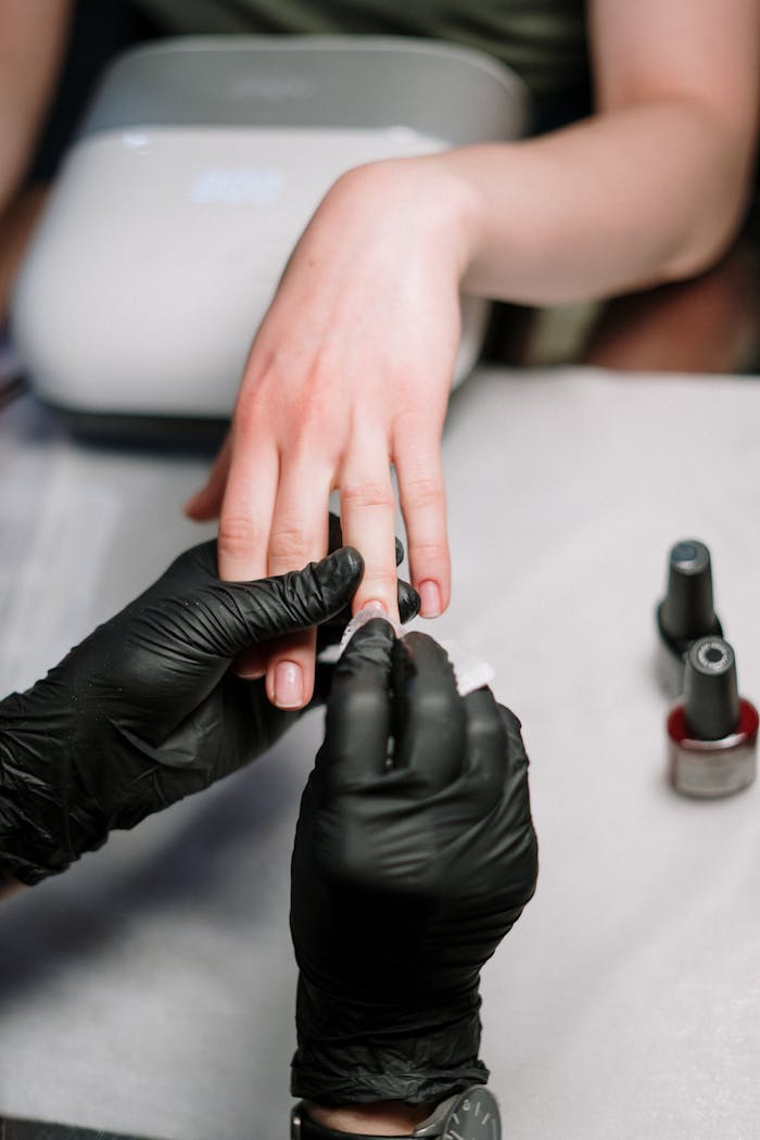 Close-up of a professional manicure with gel polish and black gloves in a salon.